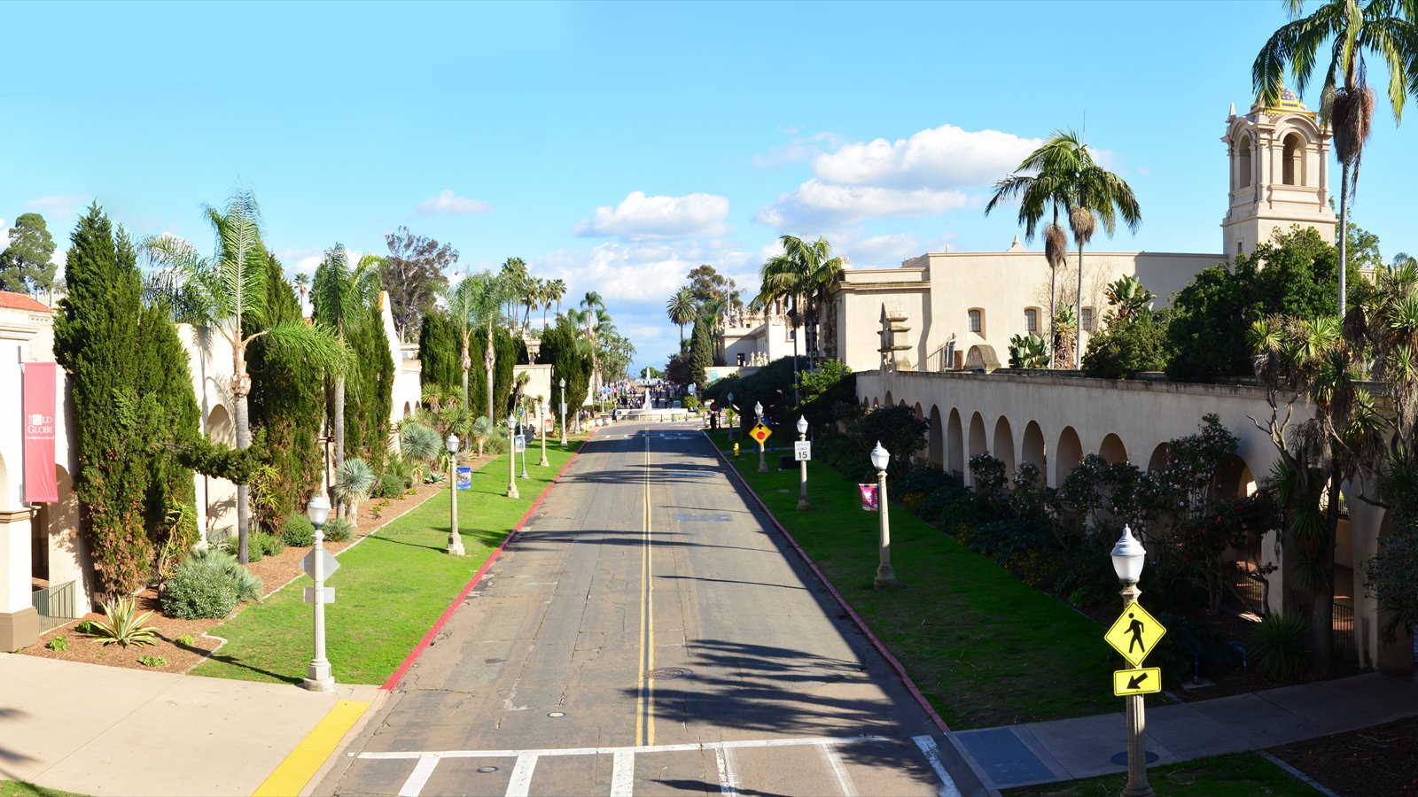 El Prado runs between arcaded historic buildings, gardens and palms in a wide elevated view of Balboa Park.