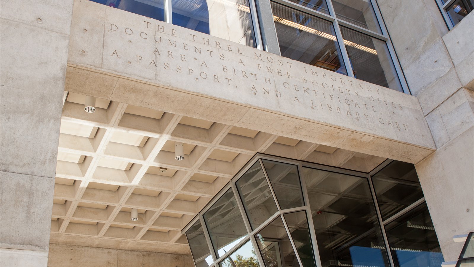 The exterior wall and lattice dome of the San Diego Central Library stand behind a quotation about library cards.
