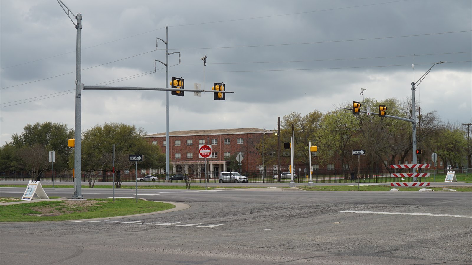 An intersection with an overhead pedestrian hybrid beacon beneath dark clouds.