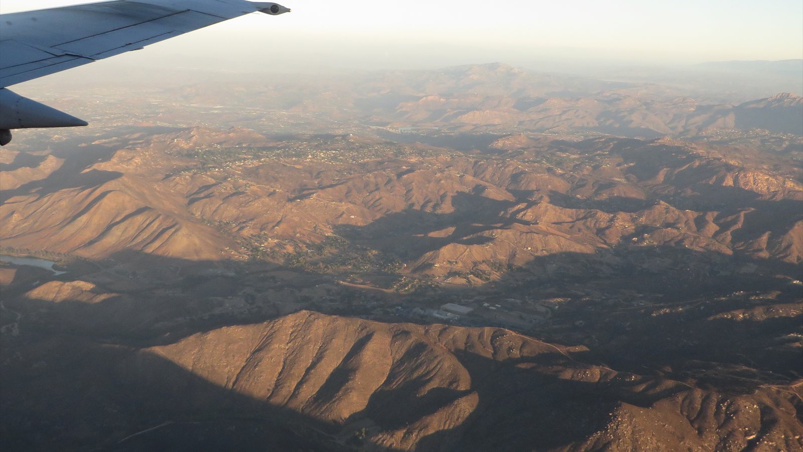 An aerial view across dry ridges, neighborhoods and a reservoir in eastern San Diego County.