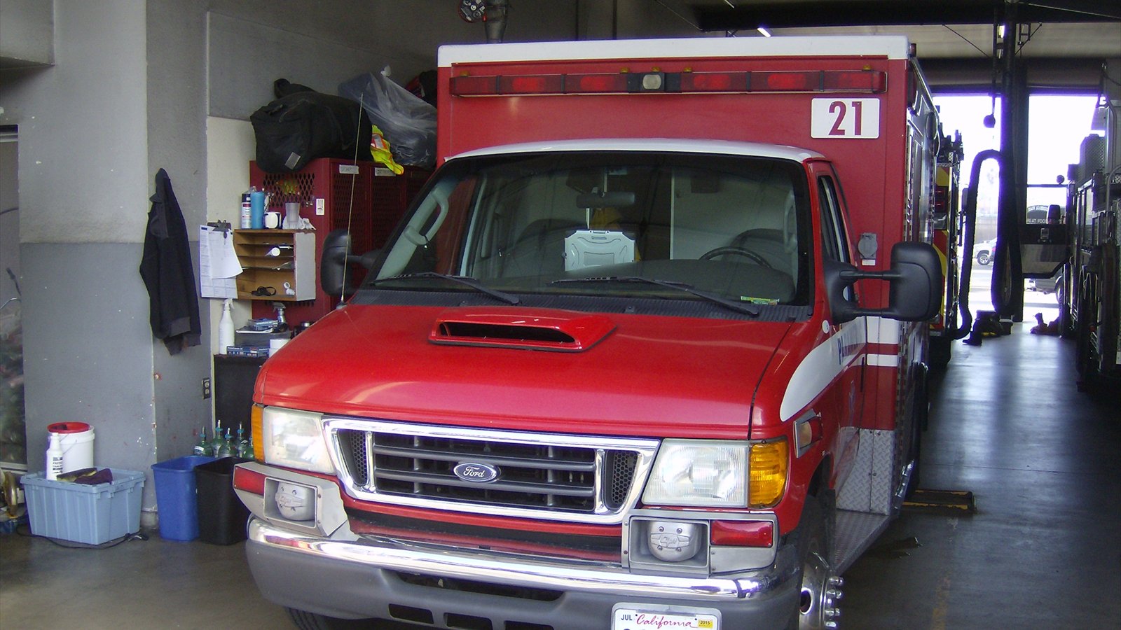 A red San Diego Fire-Rescue ambulance is parked inside a station bay.