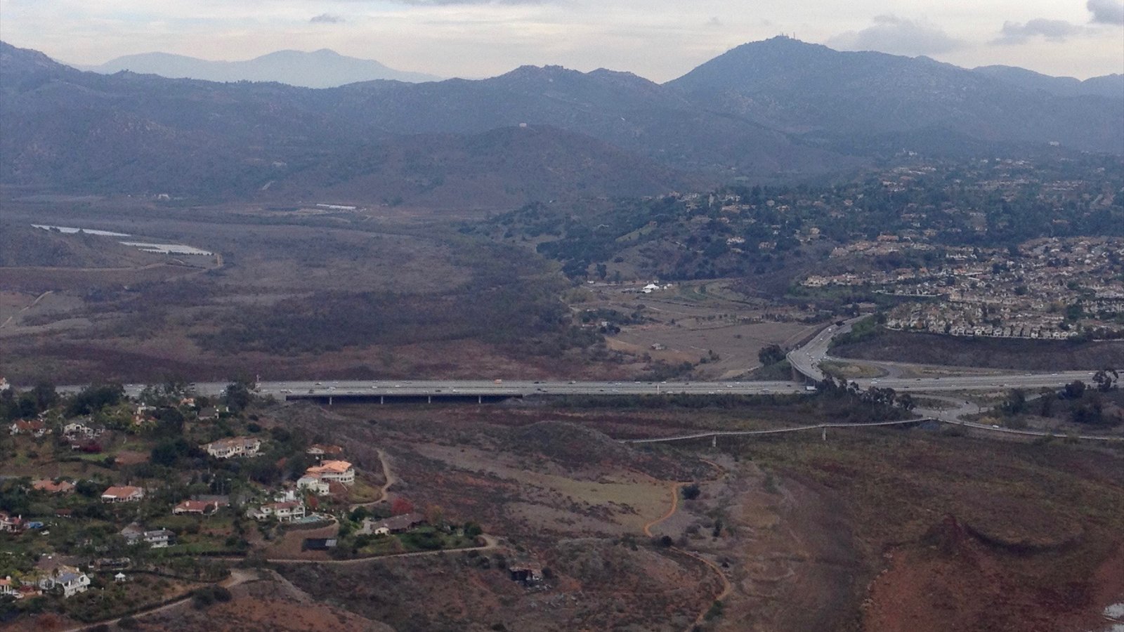 Lake Hodges Bridge (background) and David Kreitzer Lake Hodges Bicycle Pedestrian Bridge (foreground), over the nearly dry lake bed, in North San Diego County, California. View is from Bernardo Mountain, facing east…