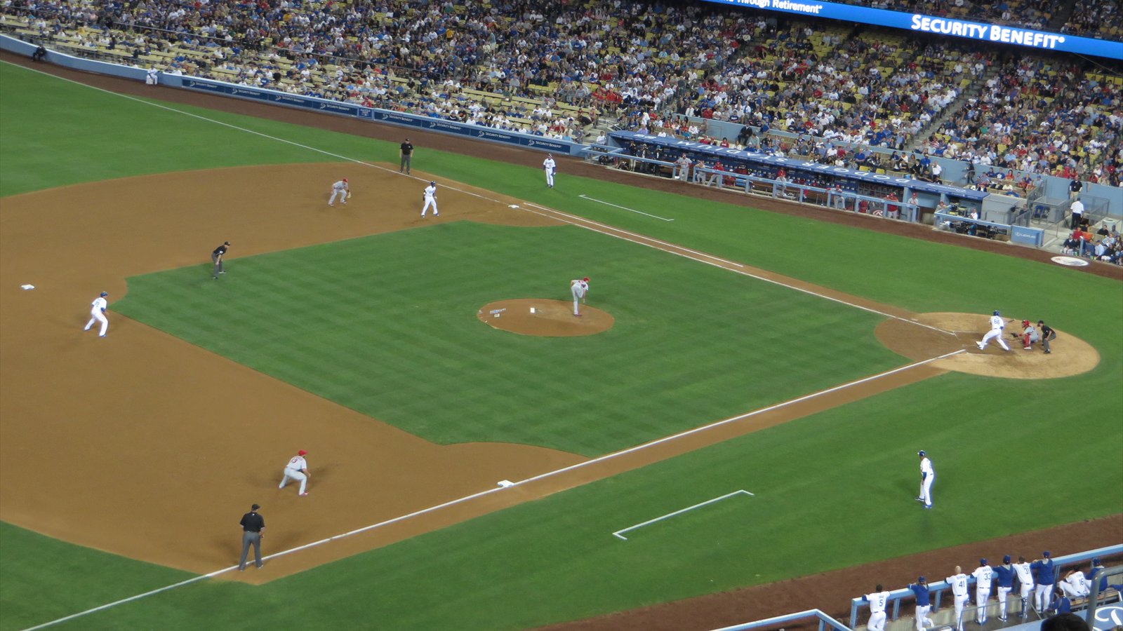 A baseball game unfolds under the lights at Dodger Stadium with players set on the field.