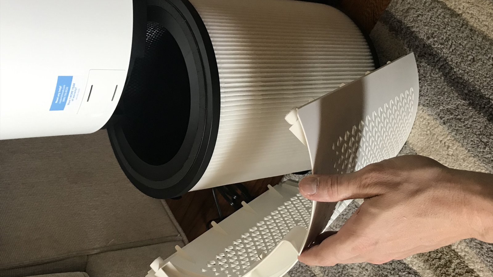 The cover of a cylindrical air purifier has been removed to expose the pleated filter inside.