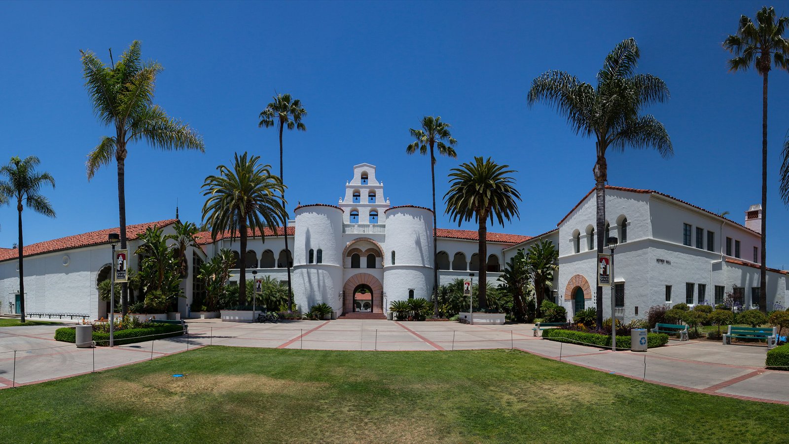 Hepner Hall's arched entrance and tiled towers rise above palms on the San Diego State campus.