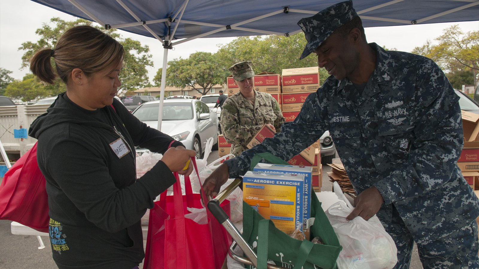 A Navy volunteer helps a shopper move groceries at a San Diego food distribution.