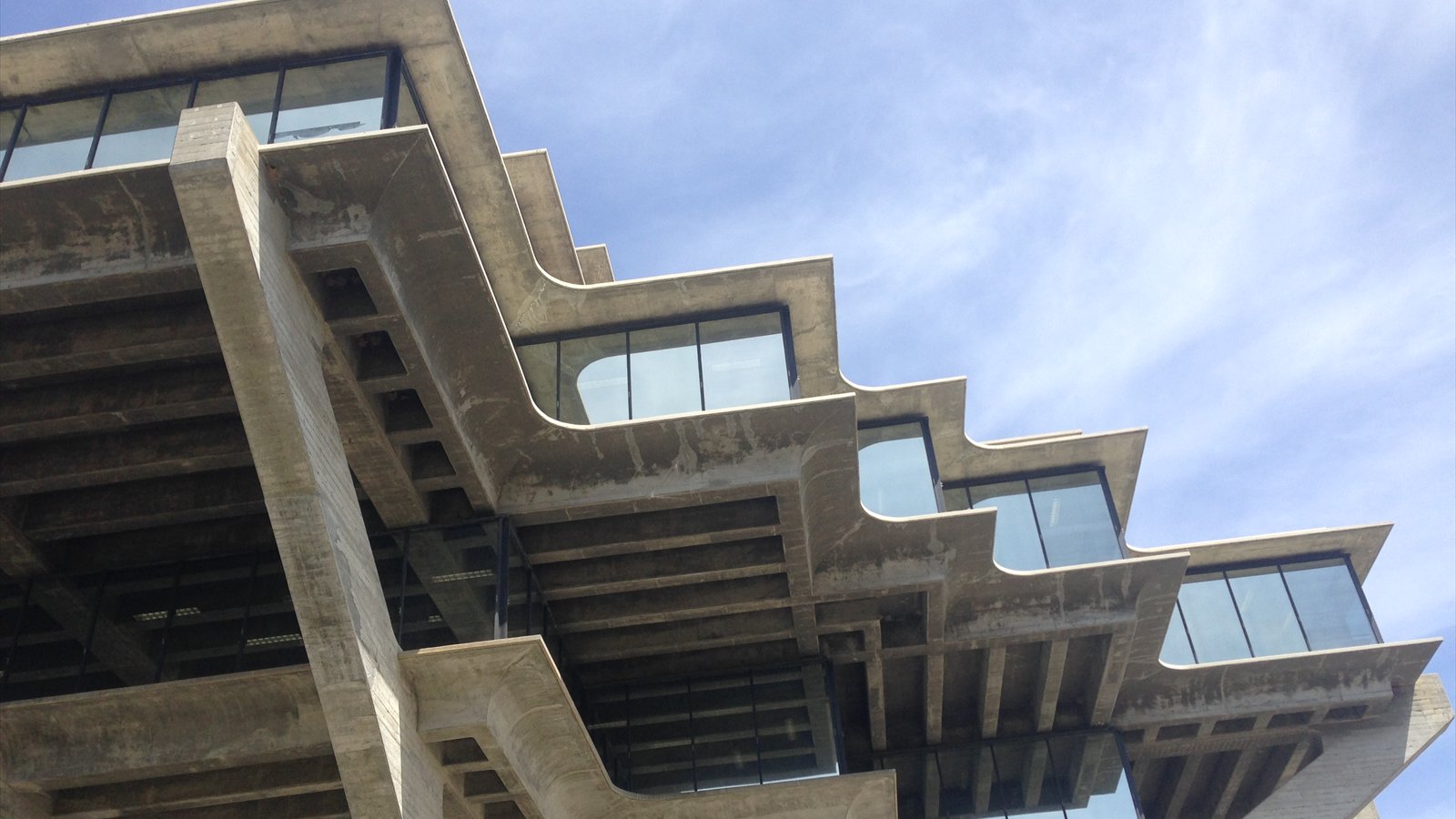 The concrete cantilevers and windows of Geisel Library viewed from below against a blue sky.