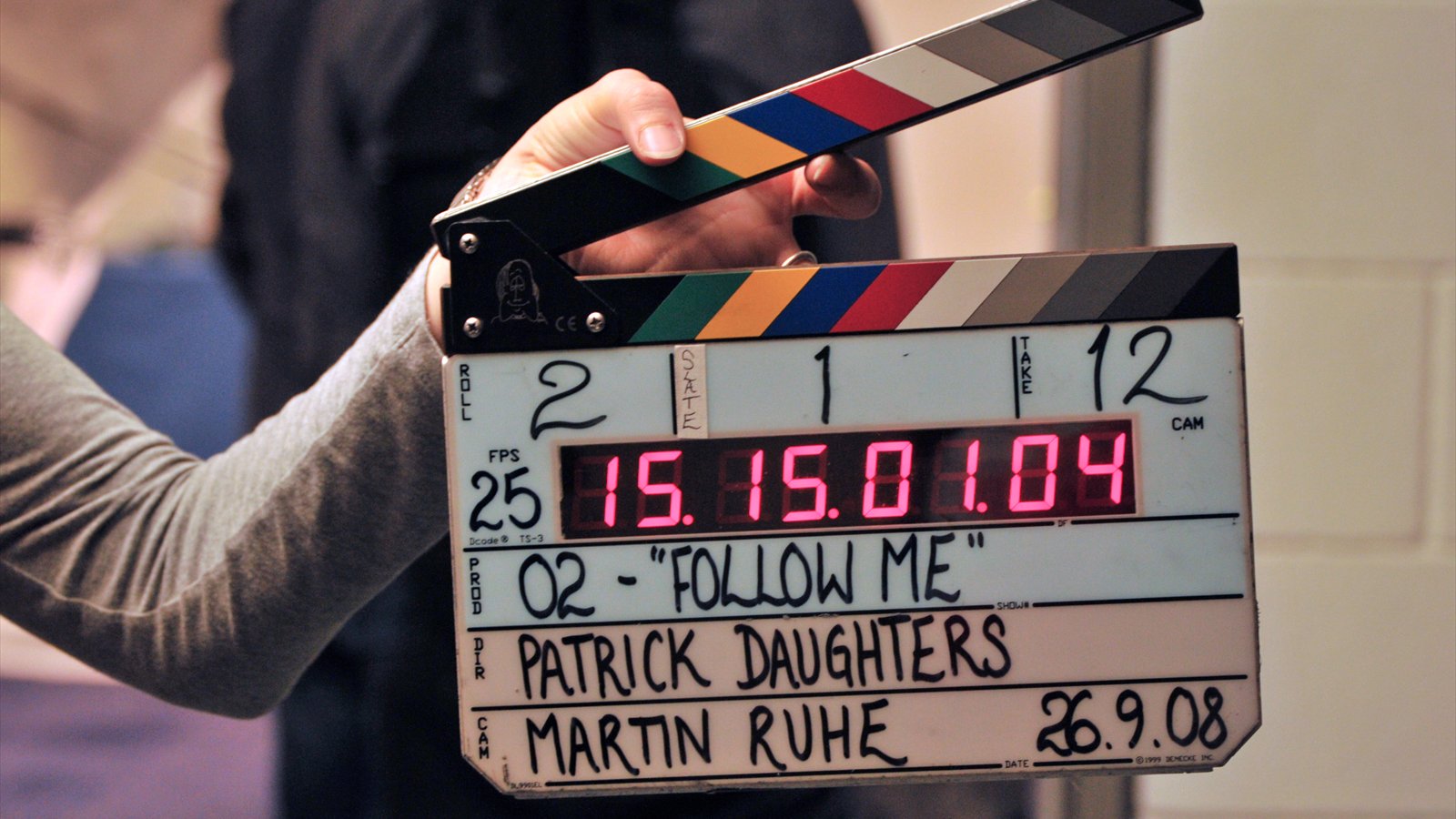 A crew member holds an open digital clapperboard during a film production.