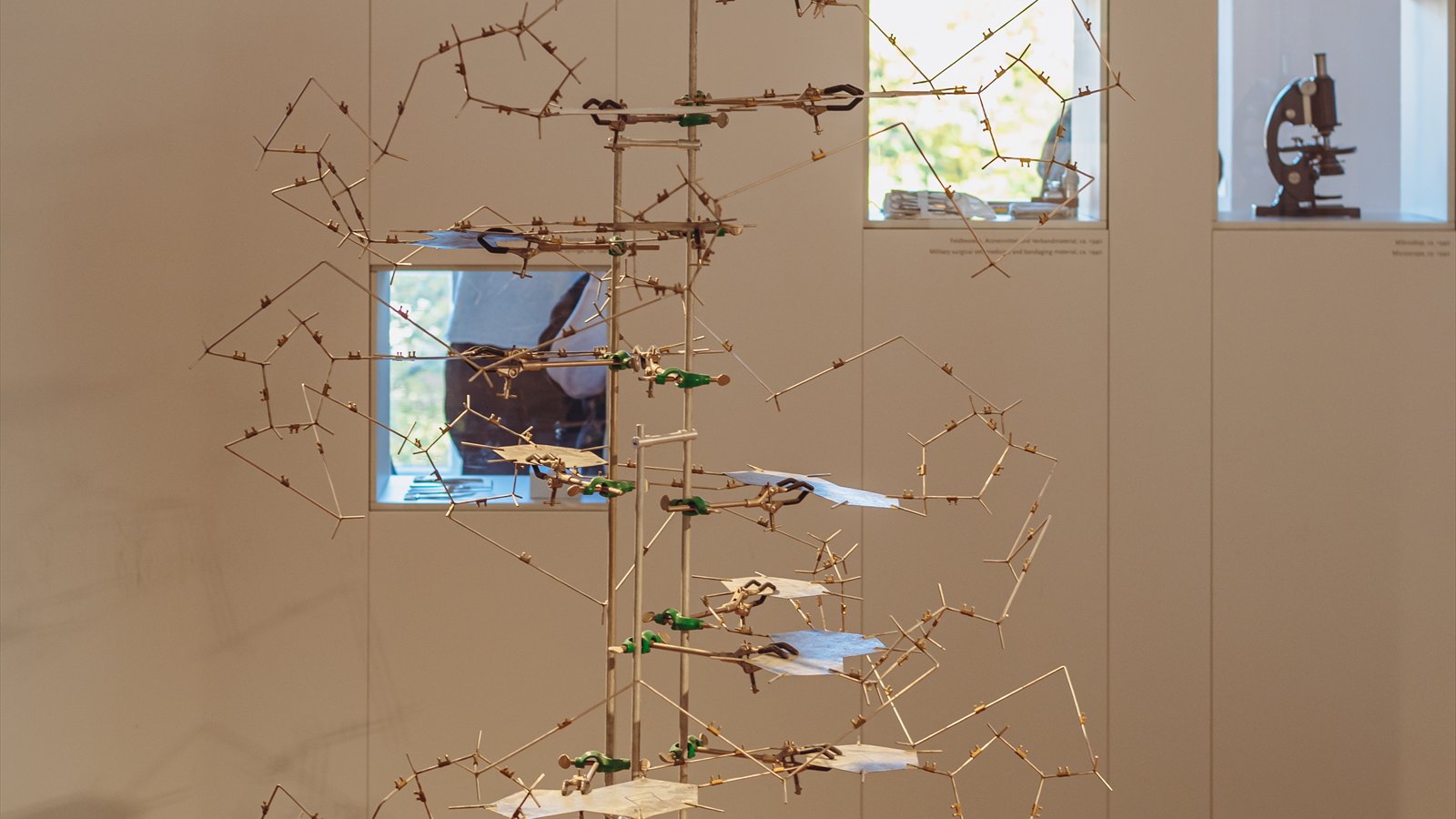 A metal and wire model of a DNA double helix displayed indoors.