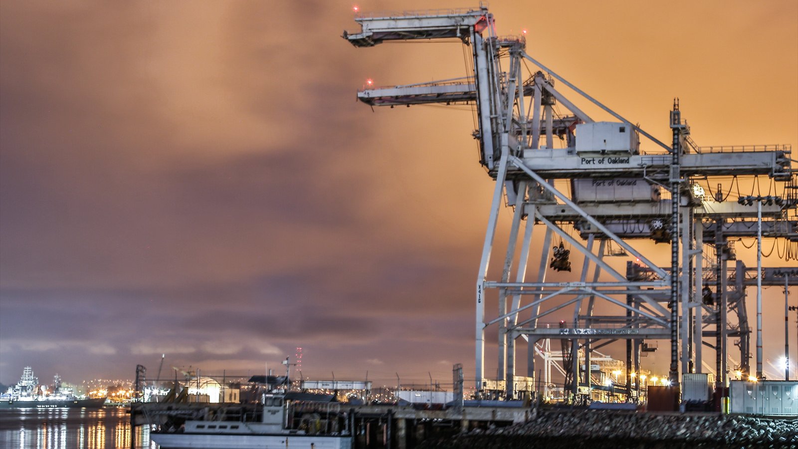 Container cranes rise above stacks of freight containers at the Port of Oakland.