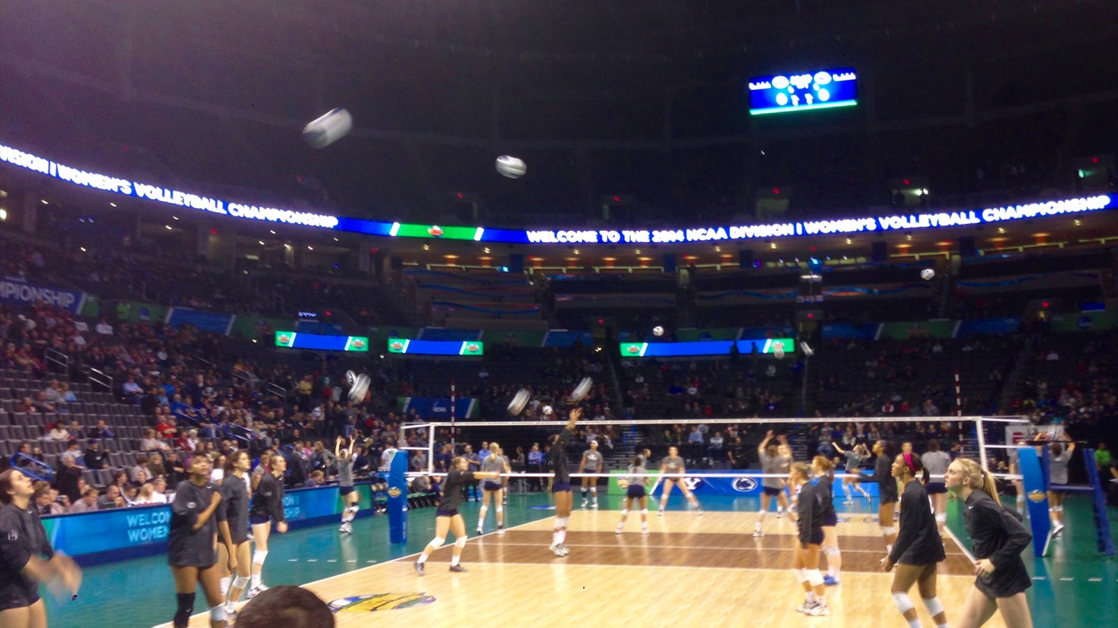 Women's volleyball players warm up on an indoor court before a championship match.