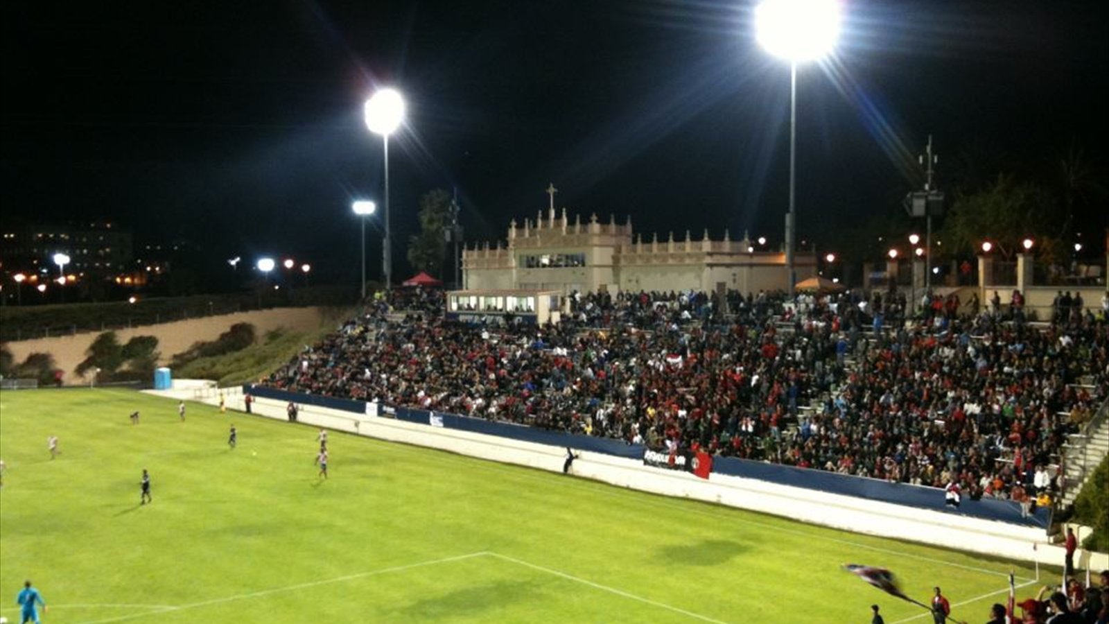 Soccer players compete on the field at Torero Stadium with fans seated in the grandstand.