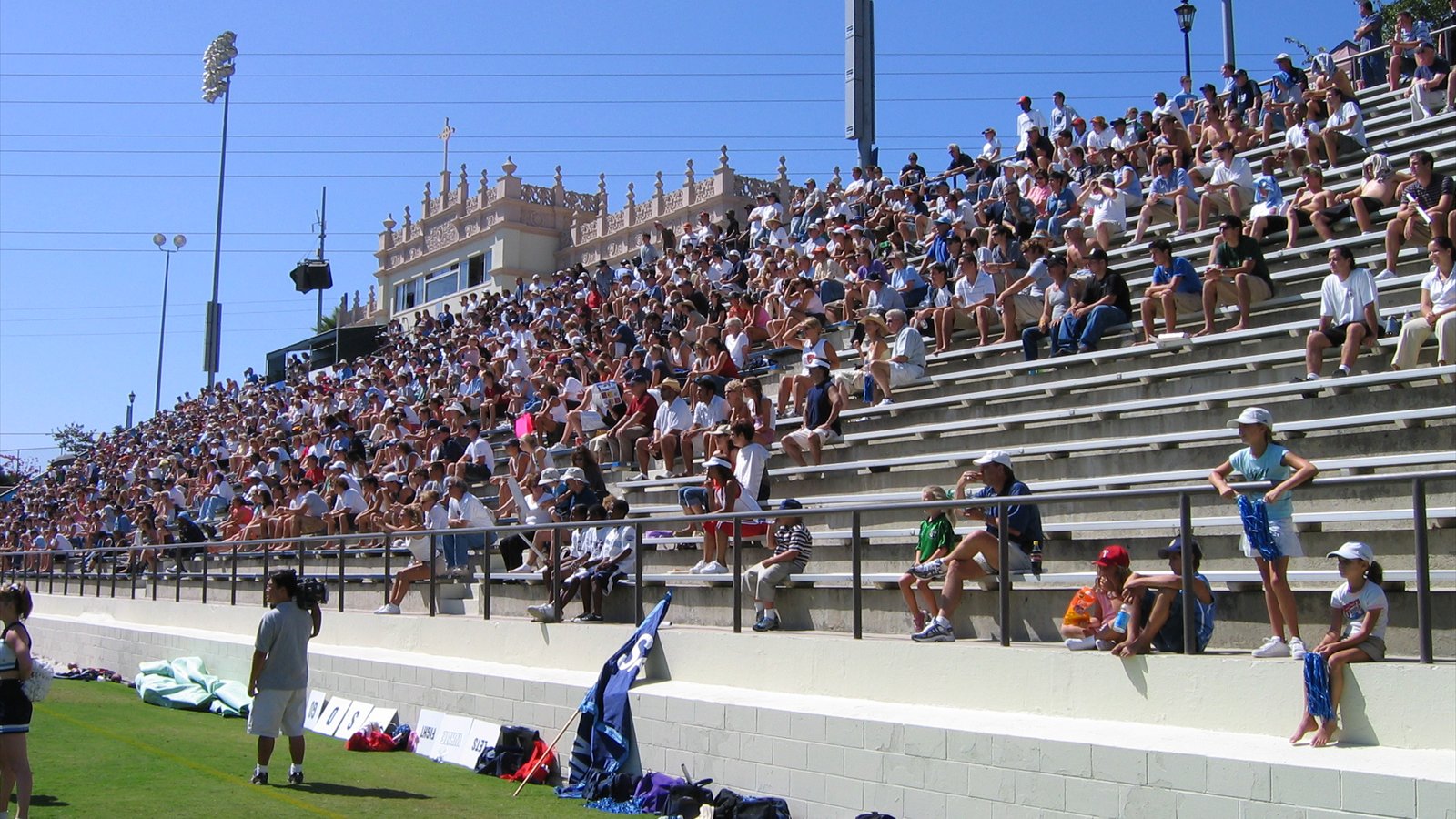 Crowded concrete grandstands rise beside the sunlit grass at Torero Stadium, with an ornate press box behind the spectators.