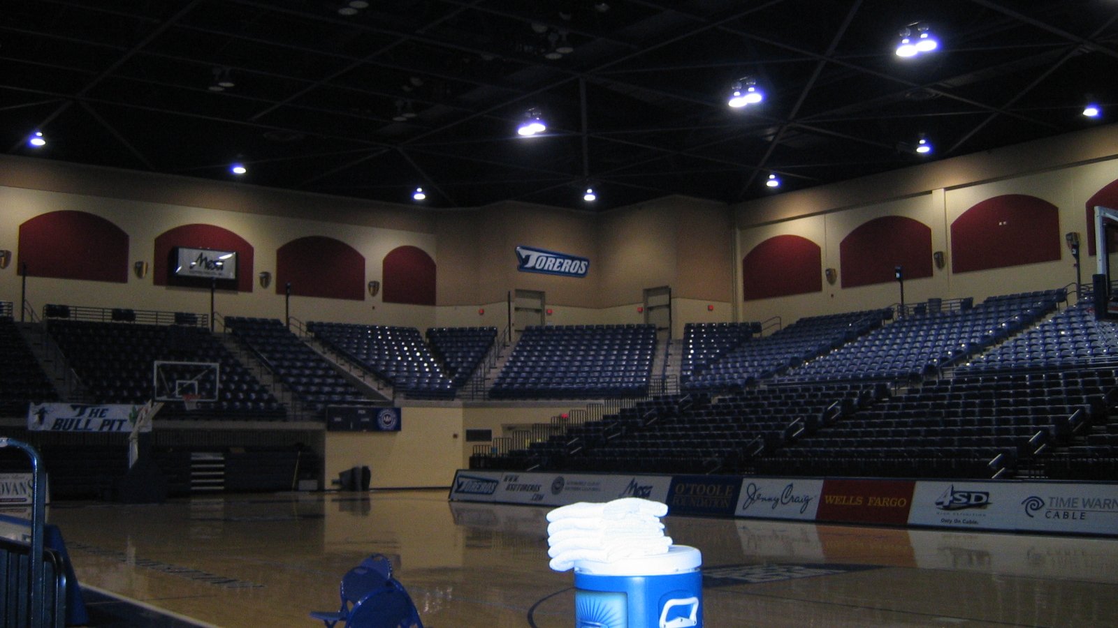 Rows of dark blue seats rise above the polished court inside the empty Jenny Craig Pavilion.