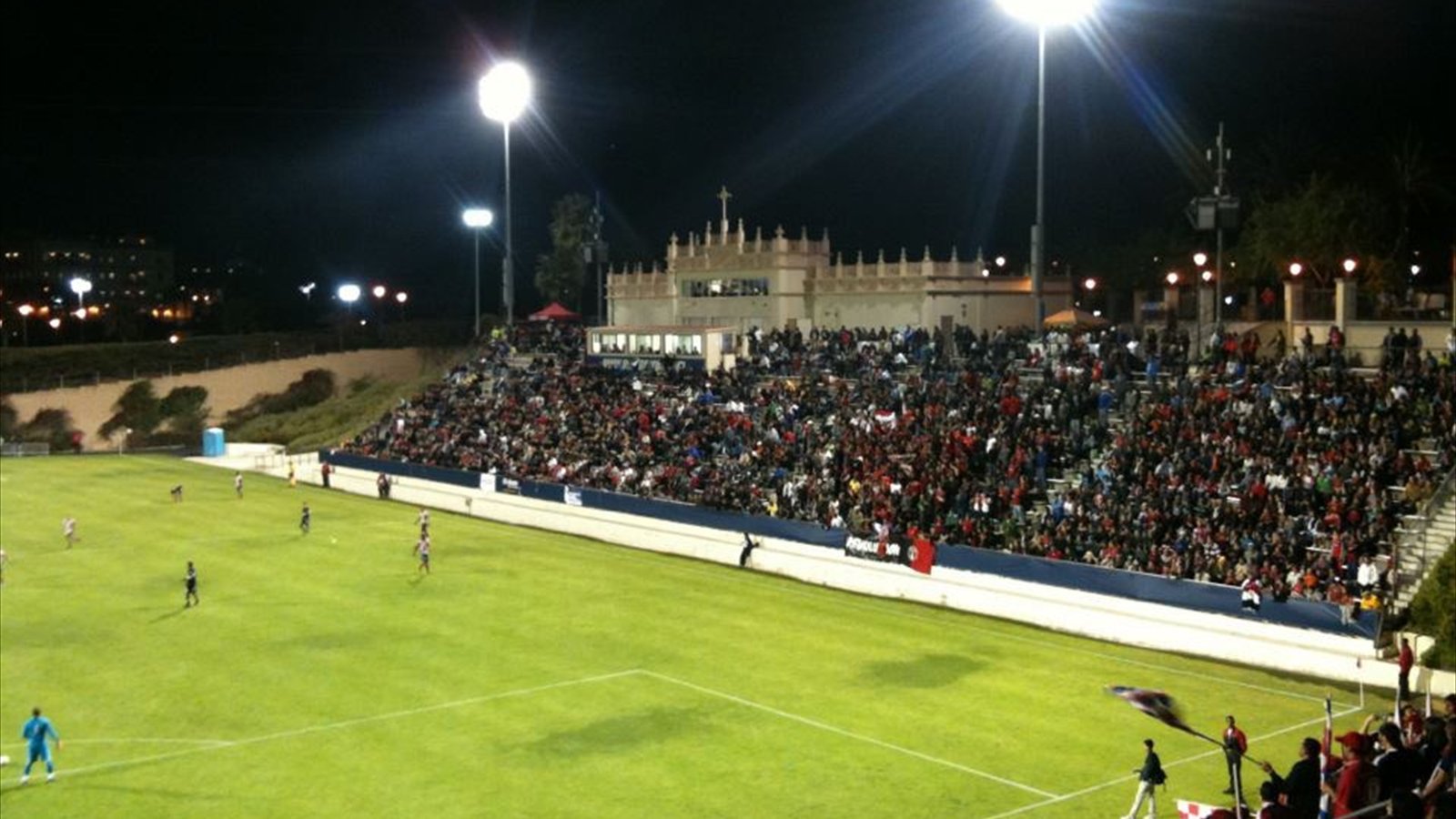 A soccer match is played on the field at Torero Stadium with spectators in the stands.